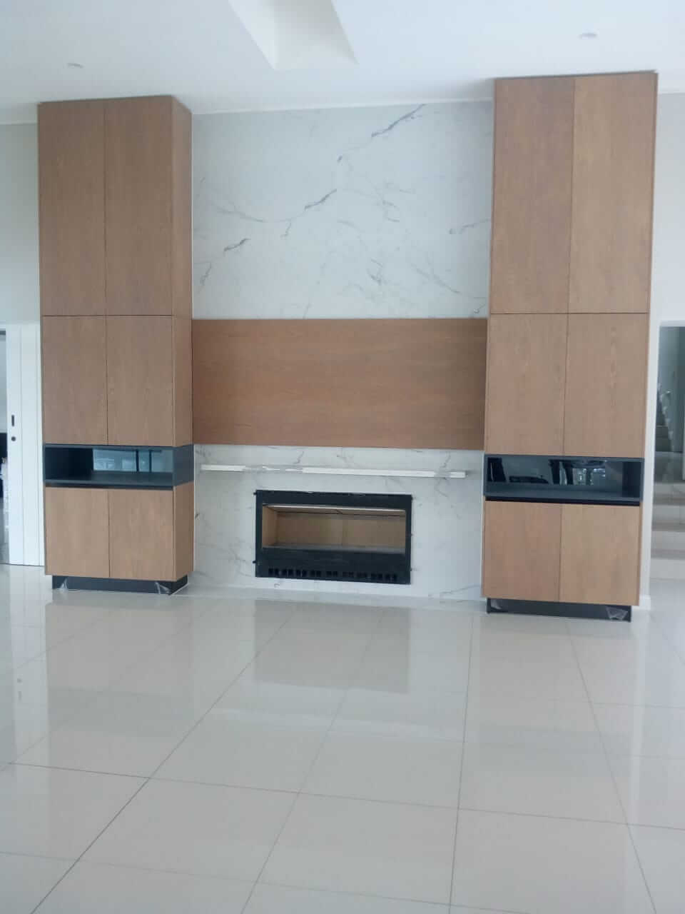 Modern fireplace with marble surround and wooden cabinets in a minimalist living room.